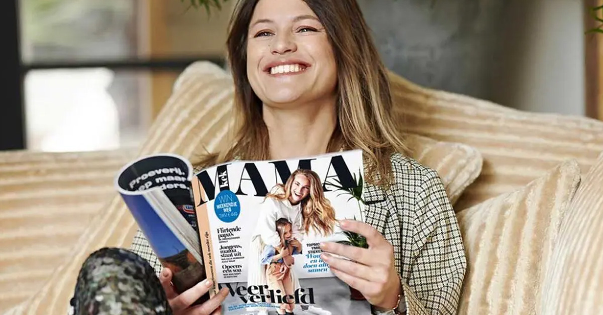 Vrolijke, jonge vrouw die een tijdschrift van Kek Mama aan het lezen is.