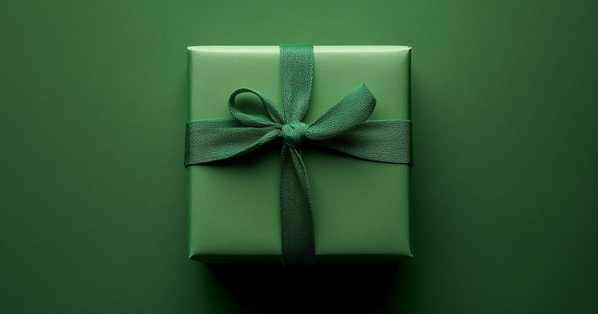 Groen cadeau op een groene achtergrond met groene strik. Cadeau in teken van Green Friday.